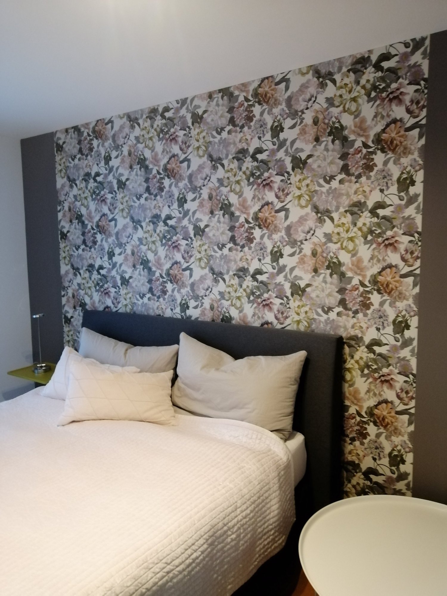 Schlafzimmer mit Blumentapete hinter dem Bett